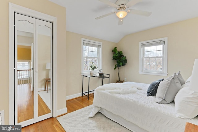 bedroom featuring multiple windows, hardwood / wood-style floors, vaulted ceiling, and ceiling fan