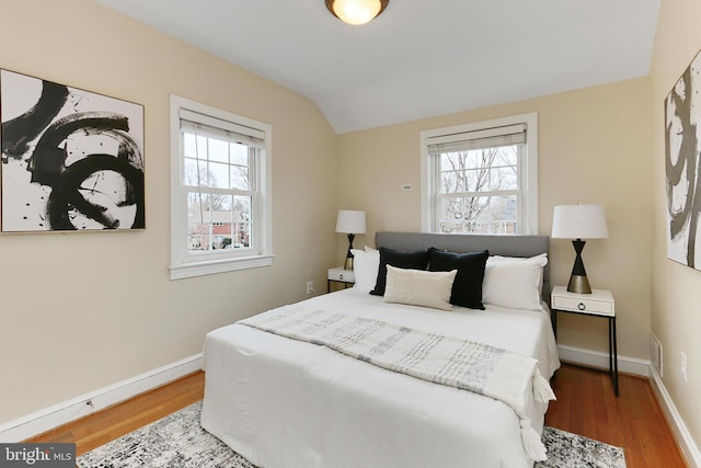 bedroom featuring multiple windows, vaulted ceiling, and hardwood / wood-style floors