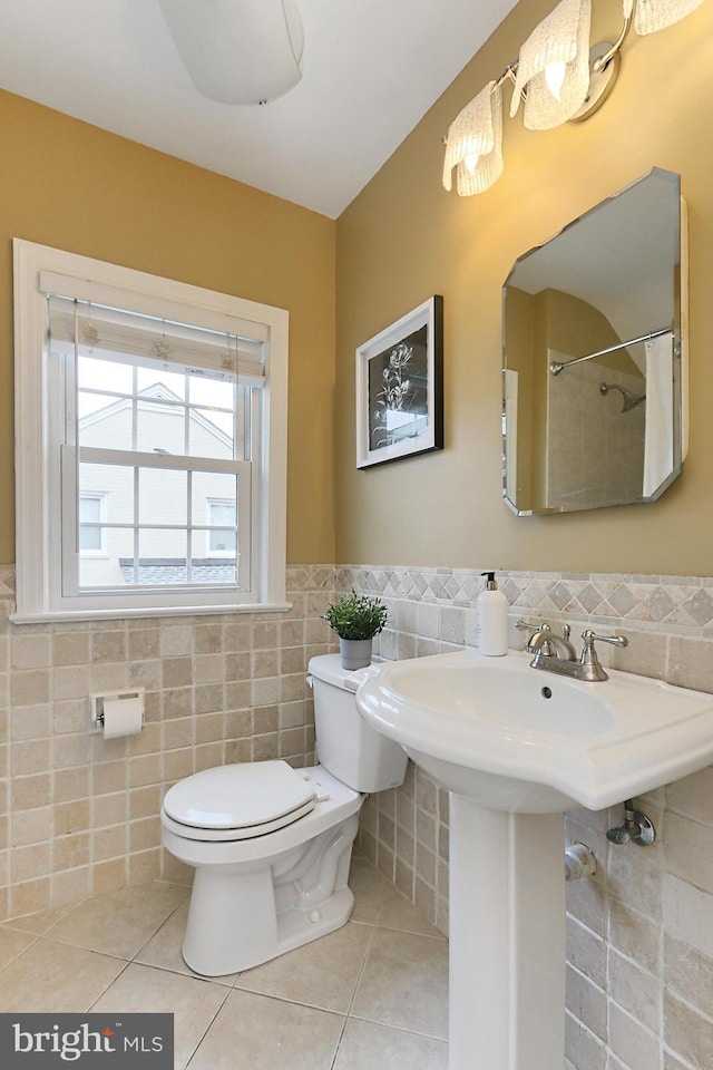 bathroom featuring tile patterned floors, toilet, curtained shower, and tile walls