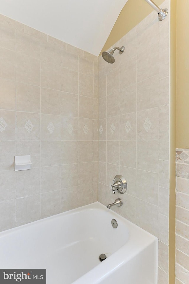 bathroom with lofted ceiling and tiled shower / bath combo