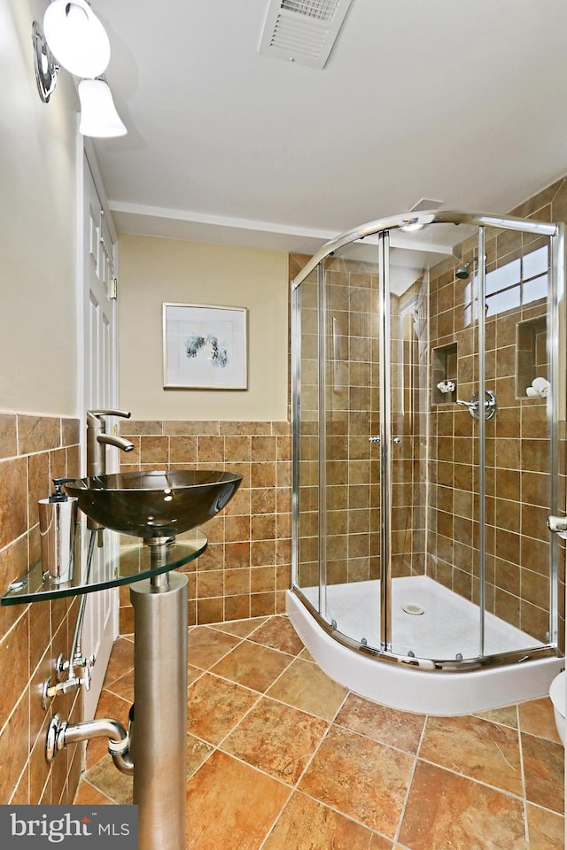 bathroom with walk in shower, sink, and tile walls