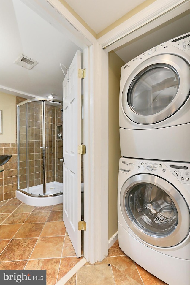 laundry room featuring tile patterned floors and stacked washer and clothes dryer