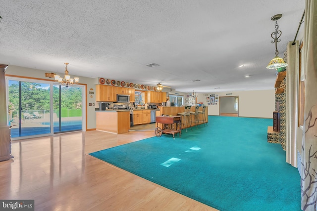 interior space with ceiling fan with notable chandelier, a textured ceiling, and light wood-type flooring