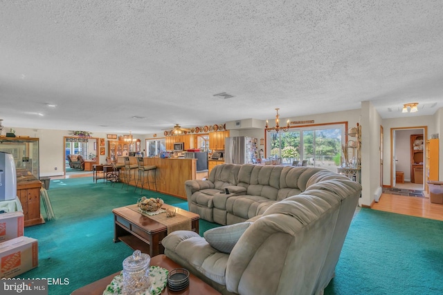 carpeted living room with a notable chandelier and a textured ceiling