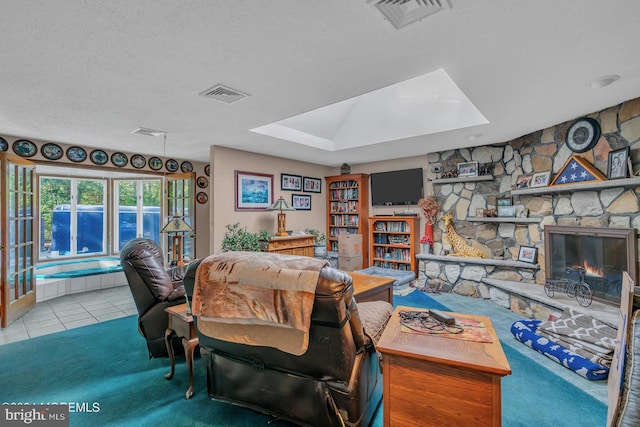 living room with light tile patterned flooring, a textured ceiling, a fireplace, and a skylight