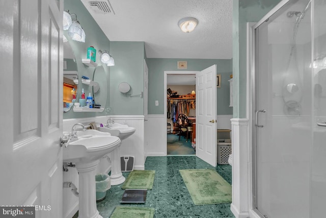 bathroom featuring a shower with shower door, sink, and a textured ceiling