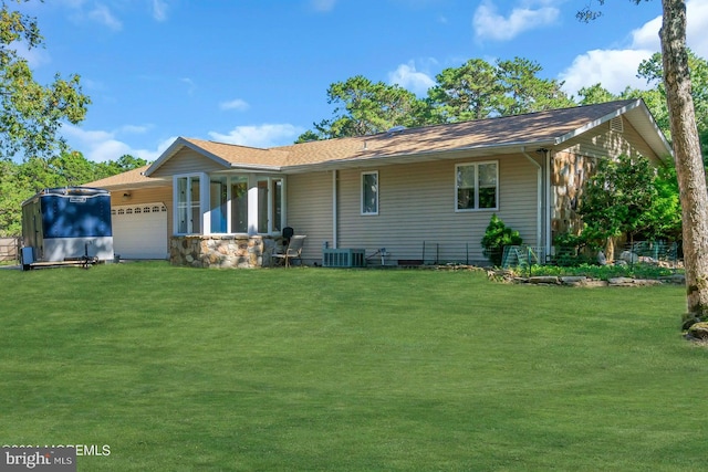 back of house with central AC unit, a garage, and a lawn