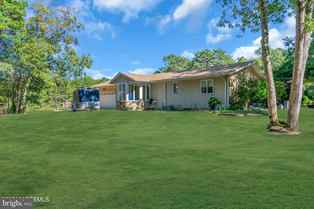 view of front of home featuring a garage, a front yard, and central air condition unit