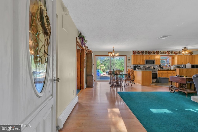 entryway with a baseboard heating unit, a chandelier, a textured ceiling, and light wood-type flooring