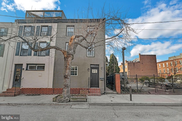 townhome / multi-family property featuring a fenced front yard, entry steps, and stucco siding