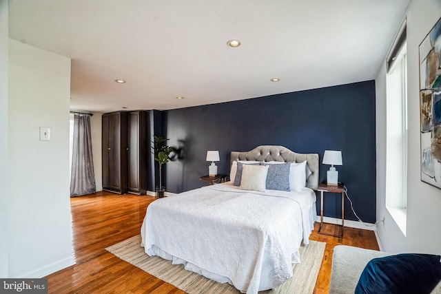 bedroom with baseboards, wood finished floors, and recessed lighting