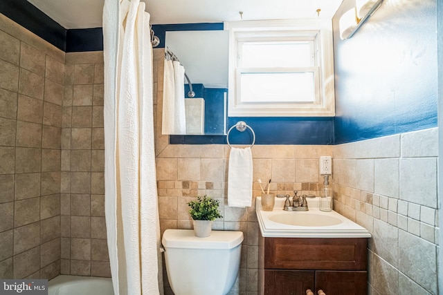 bathroom with vanity, toilet, and tile walls