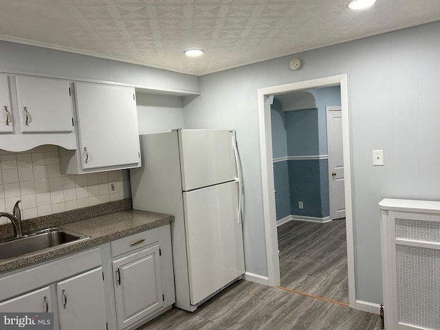 kitchen with hardwood / wood-style floors, sink, white cabinets, backsplash, and white fridge