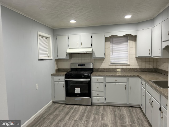 kitchen with tasteful backsplash, white cabinetry, dark wood-type flooring, and stainless steel gas range