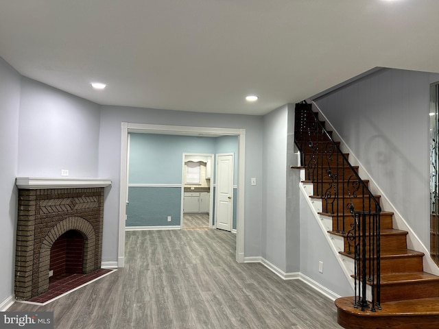 unfurnished living room featuring hardwood / wood-style flooring and a brick fireplace