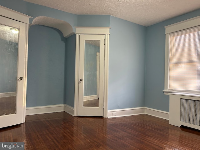 spare room with dark hardwood / wood-style floors, radiator heating unit, and a textured ceiling