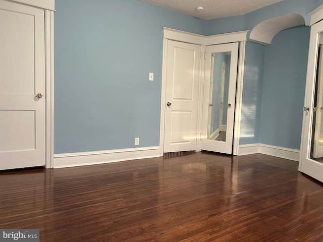 unfurnished room featuring dark wood-type flooring and a textured ceiling