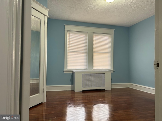 spare room with radiator heating unit, dark hardwood / wood-style flooring, and a textured ceiling