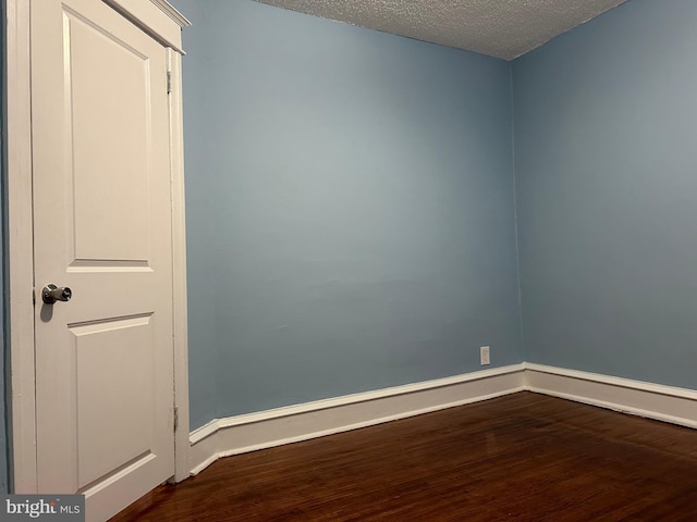 unfurnished room featuring wood-type flooring and a textured ceiling