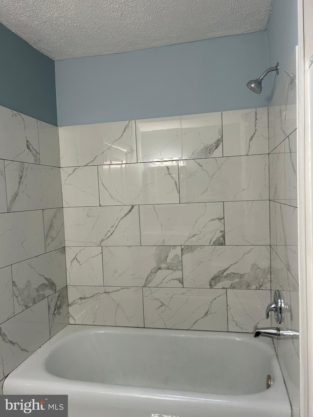 bathroom with tiled shower / bath and a textured ceiling