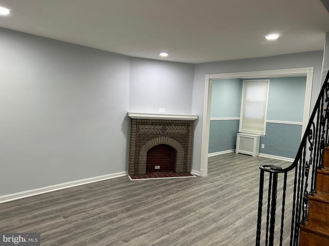 unfurnished living room with wood-type flooring, radiator, and a fireplace