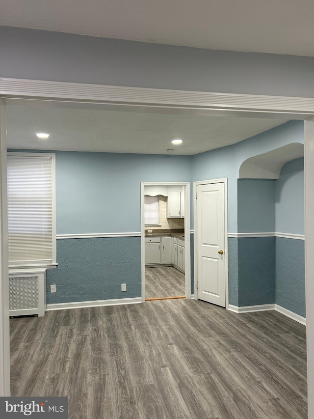 unfurnished living room featuring radiator heating unit and hardwood / wood-style floors