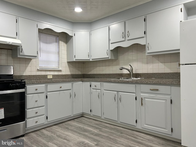 kitchen with tasteful backsplash, white cabinetry, sink, white fridge, and stainless steel gas range oven