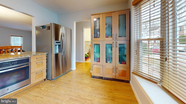 kitchen featuring stainless steel appliances, light stone countertops, light brown cabinets, and light hardwood / wood-style floors