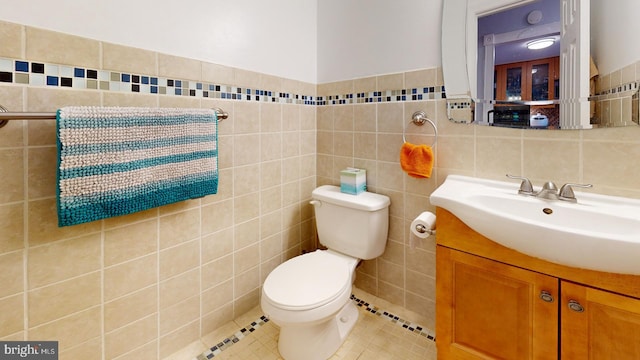 bathroom with tile patterned floors, vanity, toilet, and tile walls