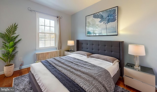 bedroom featuring radiator heating unit and dark hardwood / wood-style floors