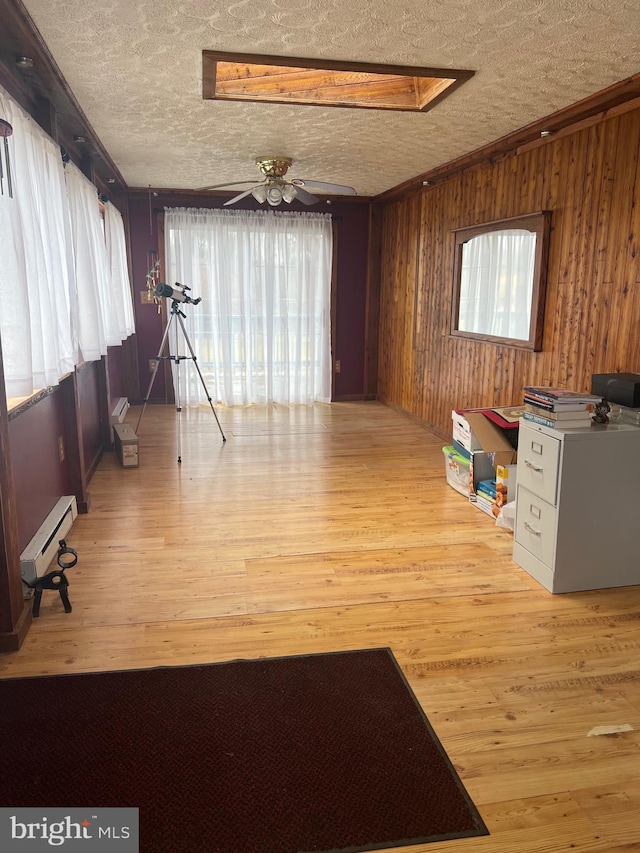 30 Foggy Bottom Ln, Berkeley Springs, WV 25411 - interior space featuring a baseboard radiator, wood walls, light hardwood / wood-style flooring, and a wealth of natural light