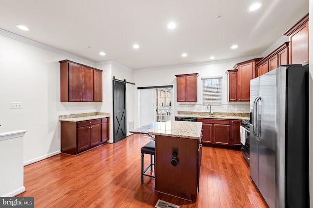 kitchen with appliances with stainless steel finishes, sink, a kitchen breakfast bar, a center island, and a barn door