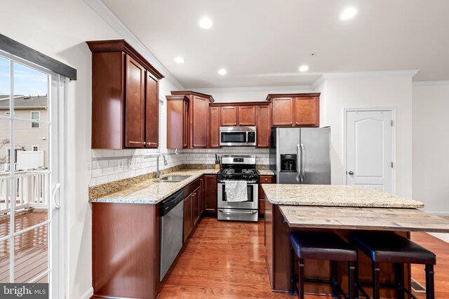 kitchen featuring sink, hardwood / wood-style flooring, backsplash, stainless steel appliances, and light stone counters