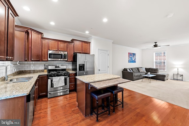 kitchen with a kitchen island, appliances with stainless steel finishes, tasteful backsplash, sink, and a kitchen bar