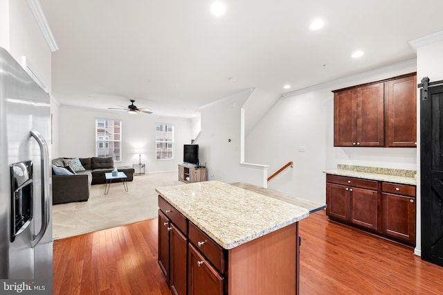 kitchen featuring dark hardwood / wood-style floors, ornamental molding, a center island, stainless steel fridge with ice dispenser, and light stone countertops