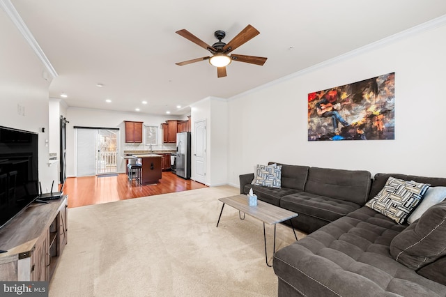 living room with ornamental molding, ceiling fan, and light wood-type flooring