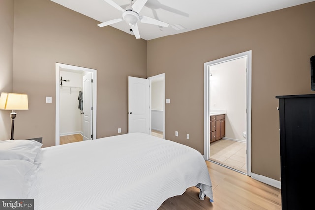 bedroom featuring ceiling fan, ensuite bathroom, light hardwood / wood-style floors, a spacious closet, and a closet