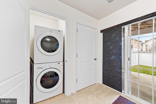 clothes washing area featuring light colored carpet and stacked washer / dryer