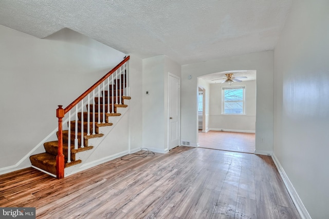 interior space featuring ceiling fan, wood-type flooring, and a textured ceiling