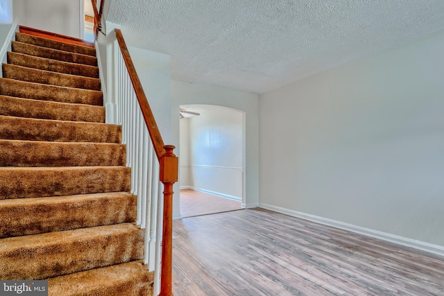 stairway featuring wood-type flooring and a textured ceiling