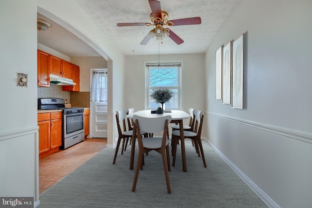 dining space featuring ceiling fan, a textured ceiling, and light parquet flooring