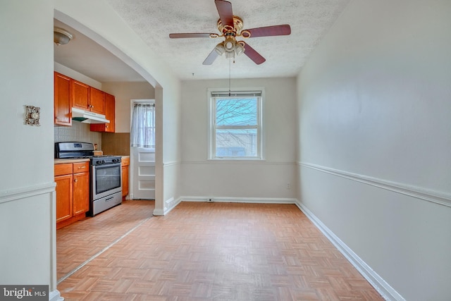 kitchen with light parquet flooring, decorative backsplash, ceiling fan, stainless steel gas range oven, and a textured ceiling