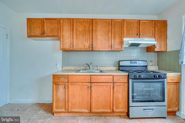 kitchen with stainless steel gas stove, sink, backsplash, and light parquet flooring