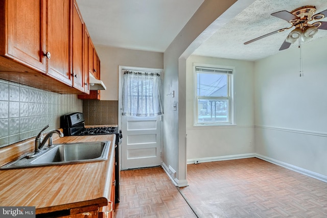 kitchen featuring sink, tasteful backsplash, a textured ceiling, black gas range, and light parquet floors