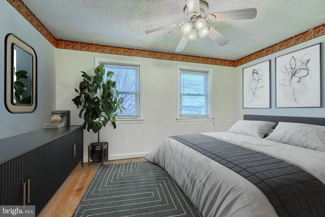 bedroom with ceiling fan, hardwood / wood-style floors, and a textured ceiling