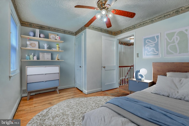 bedroom with multiple windows, ceiling fan, hardwood / wood-style flooring, and a textured ceiling