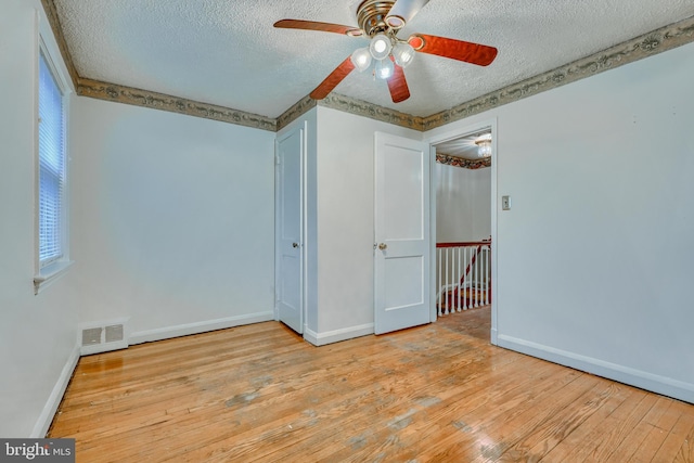 unfurnished bedroom with multiple windows, ceiling fan, a textured ceiling, and light hardwood / wood-style floors