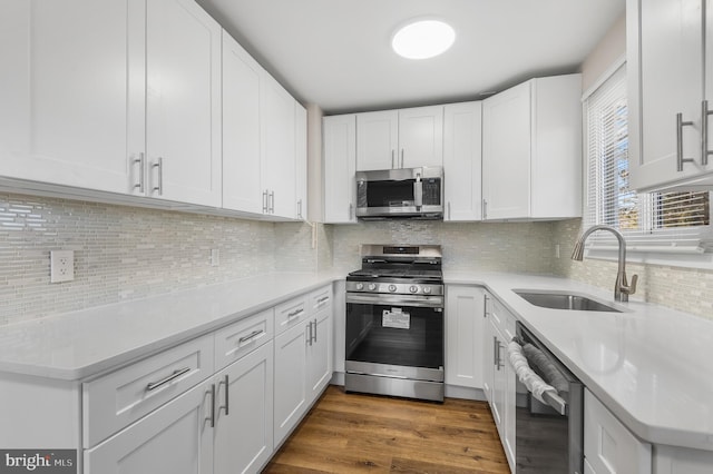 kitchen featuring sink, tasteful backsplash, appliances with stainless steel finishes, dark hardwood / wood-style floors, and white cabinets