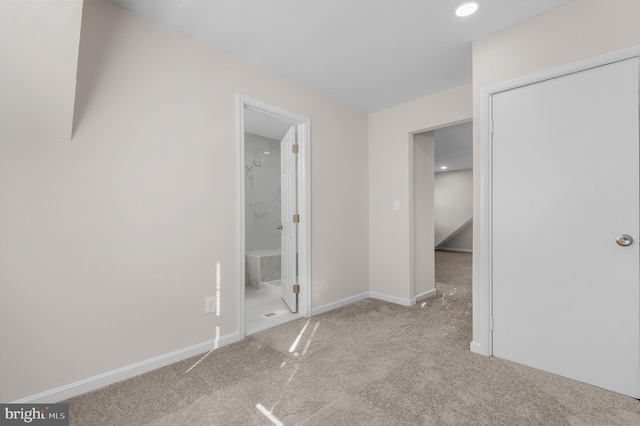 interior space featuring ensuite bath and light colored carpet