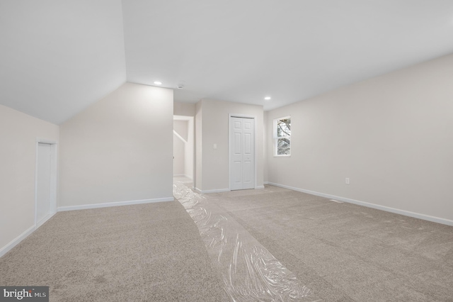 bonus room with vaulted ceiling and light carpet